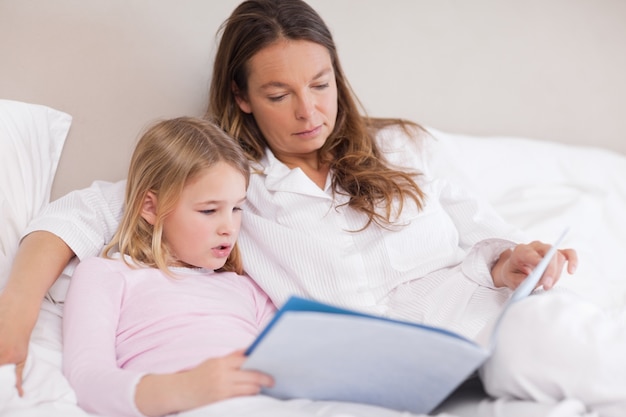 Cute girl reading a book with her mother