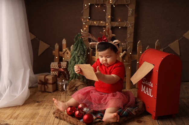 a cute girl in a red Christmas costume sends a letter to Santa Claus