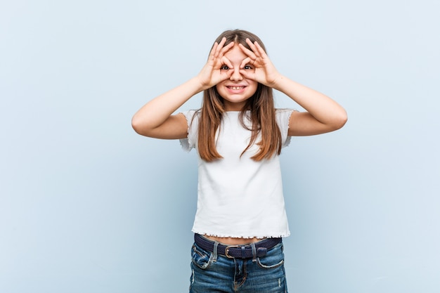 Cute girl showing okay sign over eyes