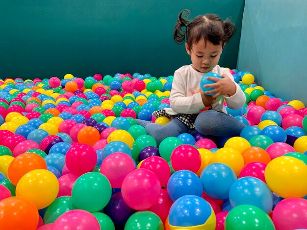 Cute girl sitting in ball pool