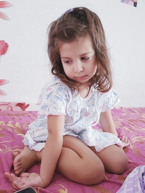 Photo cute girl sitting on bed at home