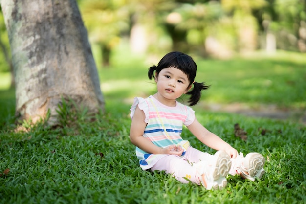 Cute girl sitting on the lawn at the garden