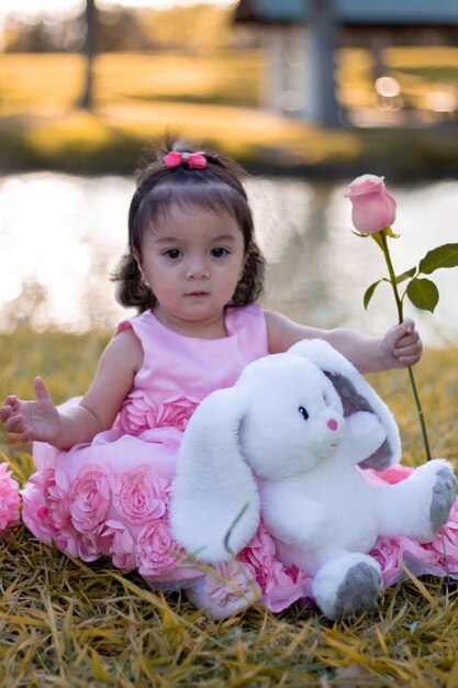 写真 ピンクの花の植物の上に座っている可愛い女の子