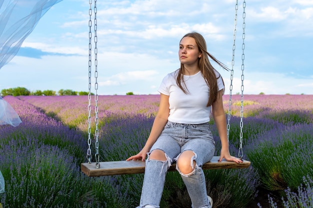 Photo cute girl sitting on a swing in a lavender field