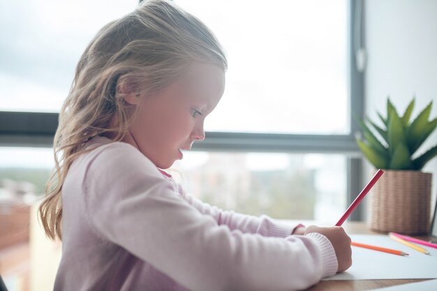 Photo a cute girl sitting at the table and drawing