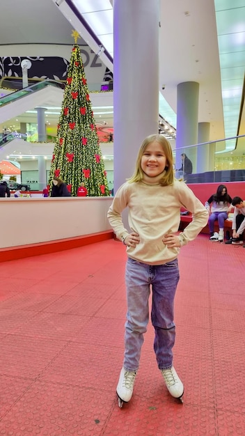 Cute girl skating at the rink in the mall for the new year