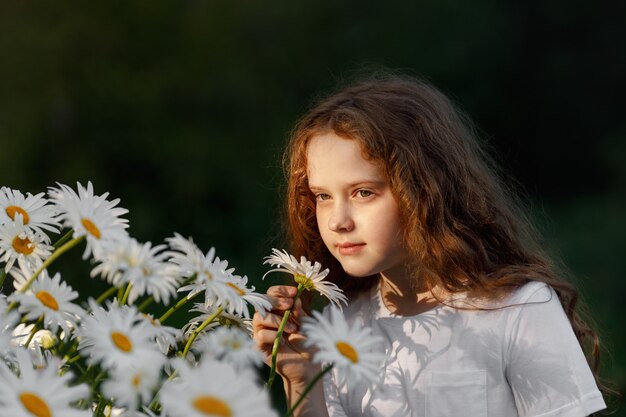 Cute girl smelling daisy flowers