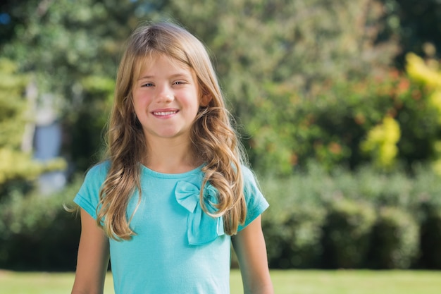 Cute girl smiling at camera in a park on sunny day