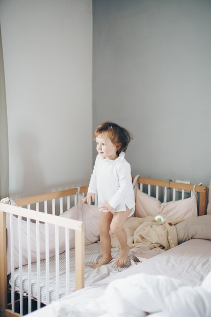 Photo cute girl standing on bed at home