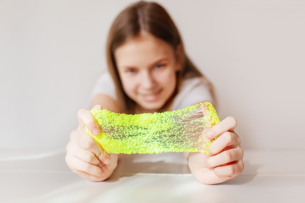 The cute girl stretches the yellow slime to the sides