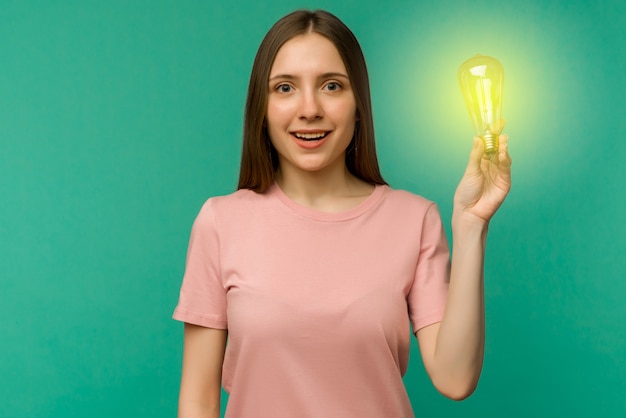 Cute girl student holds a lamp in her hand on a. The concept of an idea or creative insight.