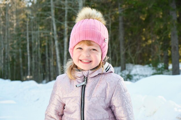 Cute girl on a sunny winter day against the backdrop of snow and forest