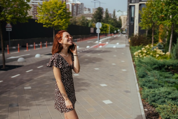 Foto ragazza sveglia che parla sul telefono cellulare sullo sfondo della città moderna