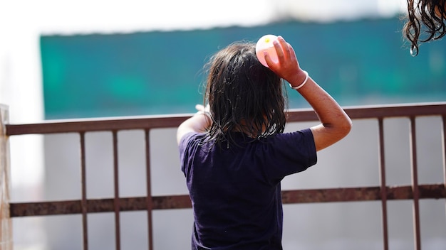 Cute girl throw water balloon outside from her house