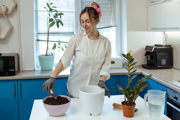 かわいい女の子が庭の手袋で家に植物を移植します歩いて、植物と新鮮な花であなたの家を飾ります