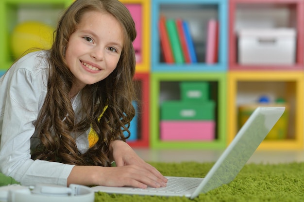 Cute girl using laptop on floor