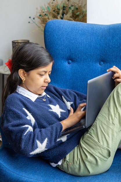 Photo cute girl using laptop while sitting on sofa