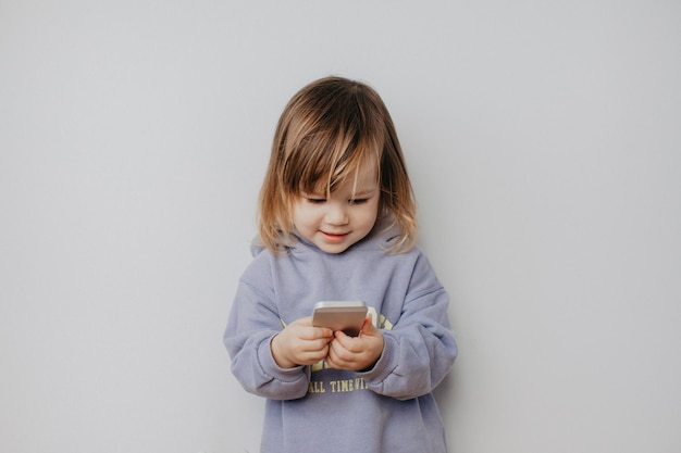 壁に立ってスマートフォンを使っているかわいい女の子