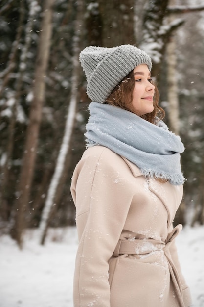 A cute girl walks through the forest in winter under the snow