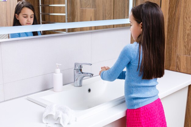 Cute girl washing hands in bathroom