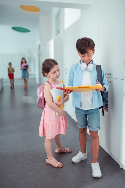 Cute girl wearing pink dress standing near handsome schoolboy