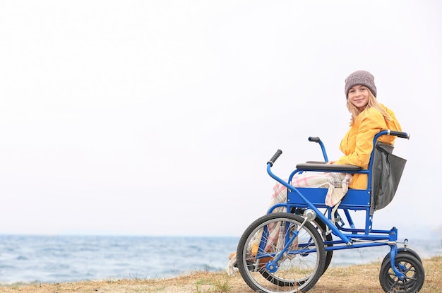 Cute girl in wheelchair on sea shore