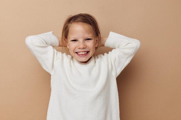 変更されていない子供の頃の手のジェスチャーをポーズする白いセーターのかわいい女の子