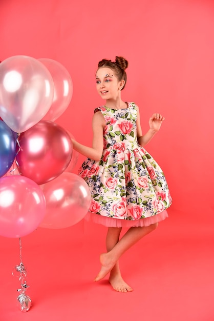 A cute girl with balloons and candy. Pink background. Party.