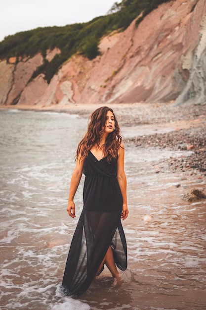 Cute girl with a black dress on the beach