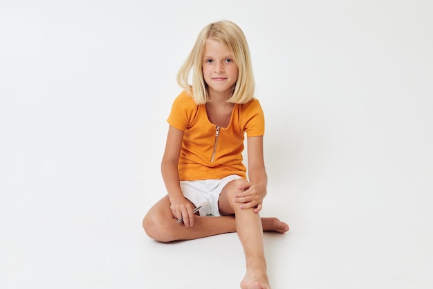 Cute girl with blond hair sitting on the floor