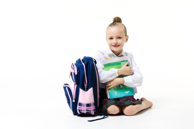 Cute girl with a book and a backpack on a white background