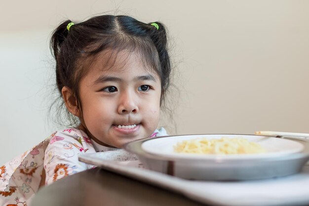 写真 テーブルの皿に食べ物を入れた可愛い女の子