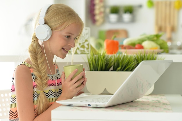 Cute girl with headphones using laptop at home