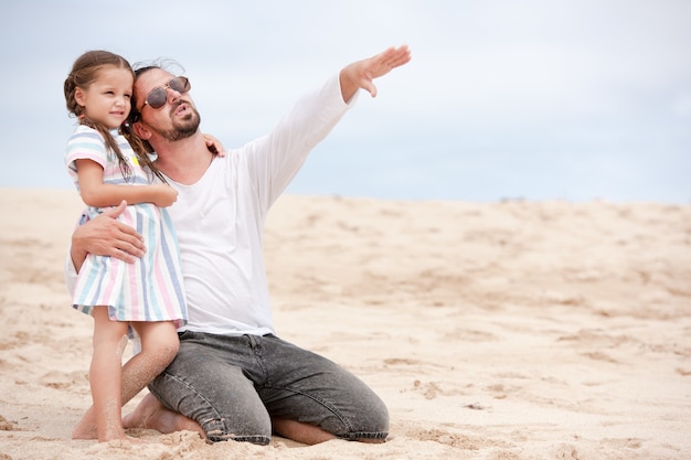 Cute girl with her happy and points to something father outdoor coast ocean