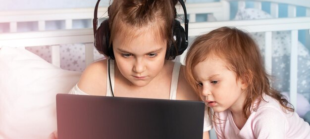 어린 여동생과 함께 노트북 컴퓨터의 스크린을 보는 귀여운 소녀 e-learning 개념