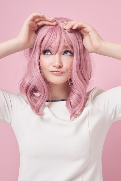Ragazza carina con lunghi capelli rosa, colorazione dei capelli. bella donna su uno sfondo rosa in un abito bianco. capelli colorati, acconciatura perfetta, bellezza e cura
