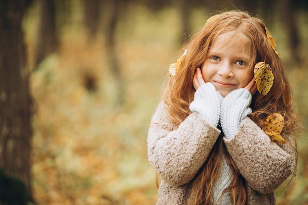Cute girl with long red hair in autumnal forest