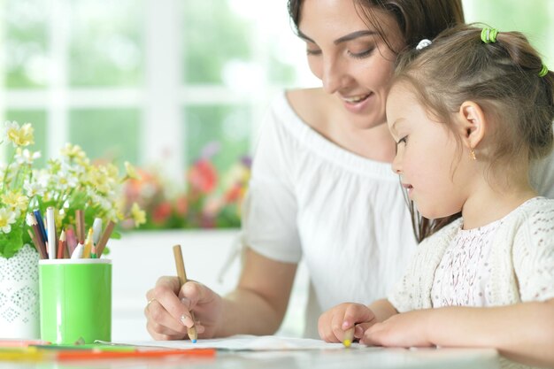 Cute girl with mother drawing at the table