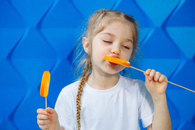 Cute girl with oranges she eats them on a blue background