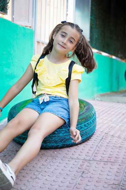 Cute girl with pigtails playing with a green painted wheel in the schoolyard