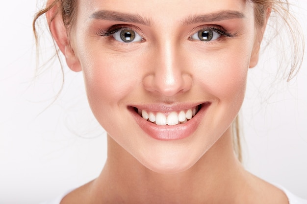 Cute girl with snow white teeth on white studio background, dentistry concept, perfect smile, looking at camera, close up.