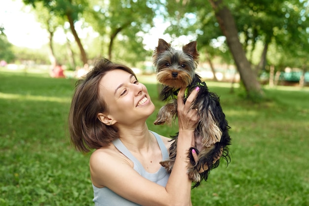 A cute girl with a square hugs a Yorkshire terrier on street.