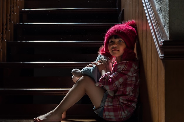 cute girl with toy sitting on steps at home