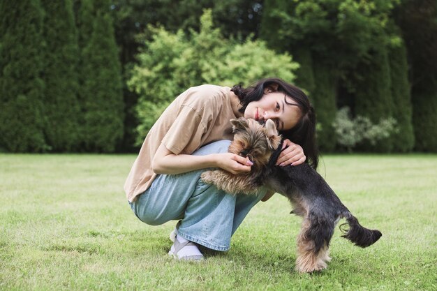 거리에 요크셔 테리어와 함께 있는 귀여운 소녀 공원에서 작은 강아지와 포옹