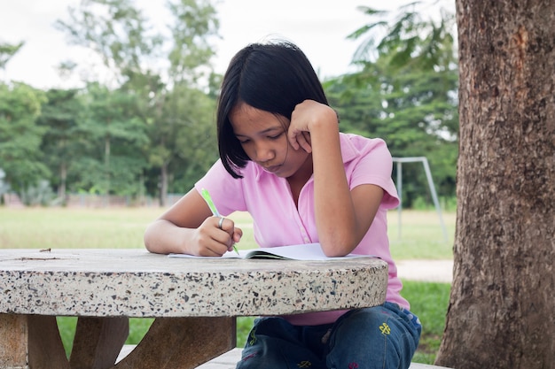 かわいい女の子が庭で本を書く