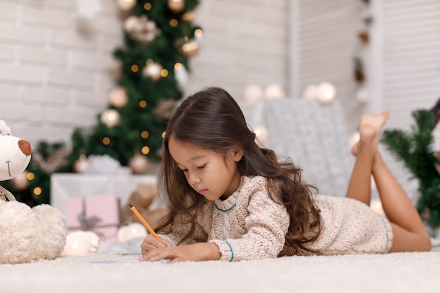 Cute girl writing a letter to Santa Claus at home