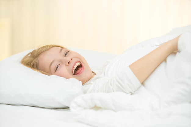 The cute girl yawn and lay on the bed