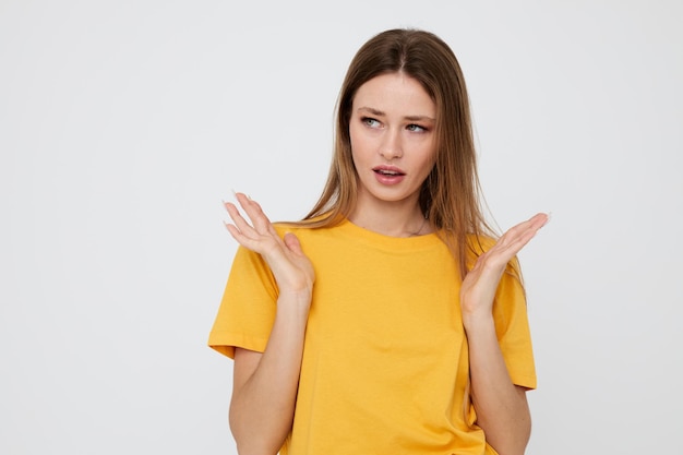 Cute girl in yellow tshirt posing hand gestures light background