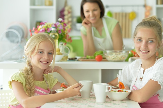 Cute girls eating delicious fresh salad in kitchen