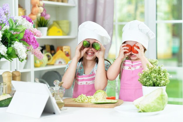 Cute girls preparing delicious fresh salad in kitchen